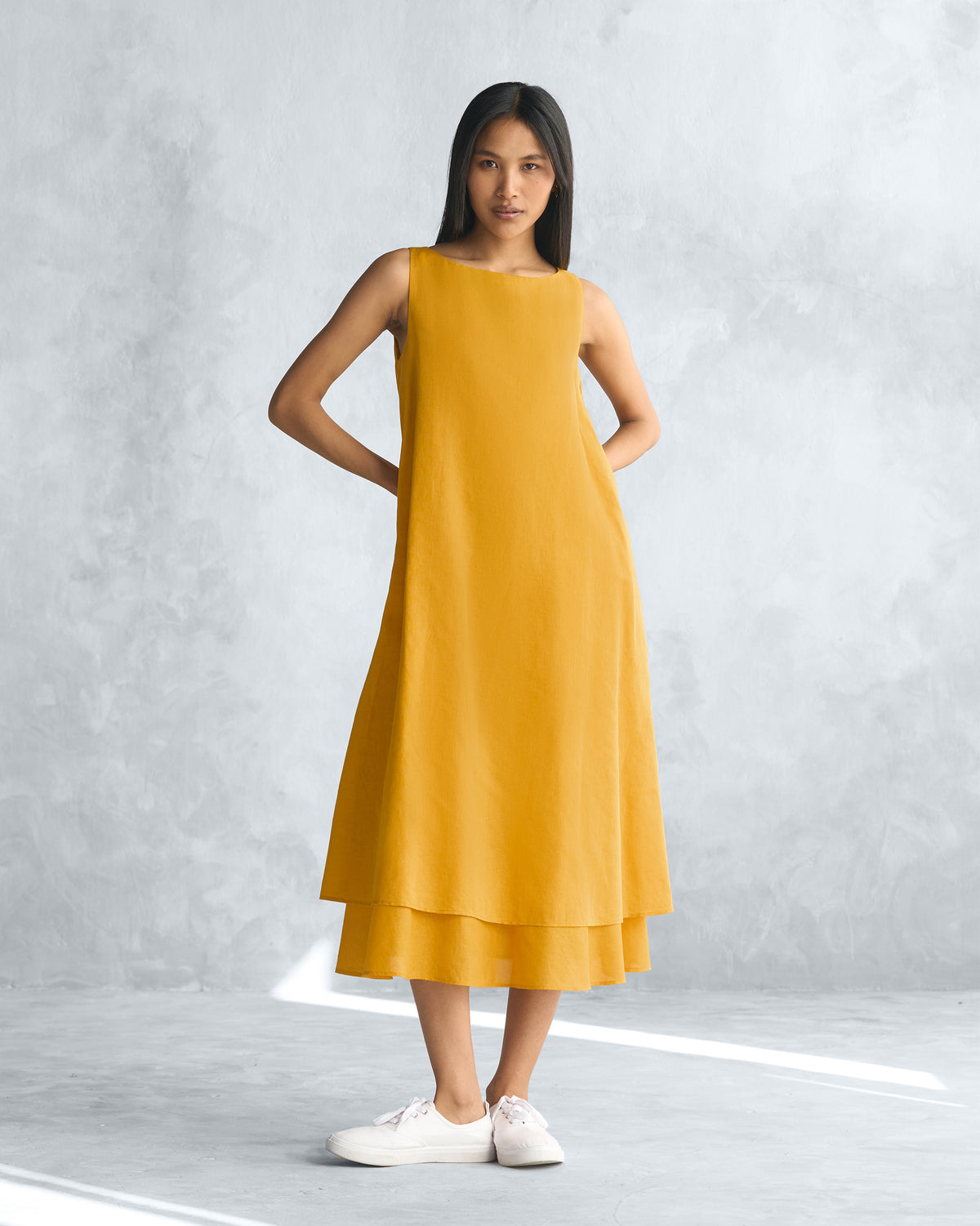 Person wearing a mustard yellow Double layer dress with a layered hem.