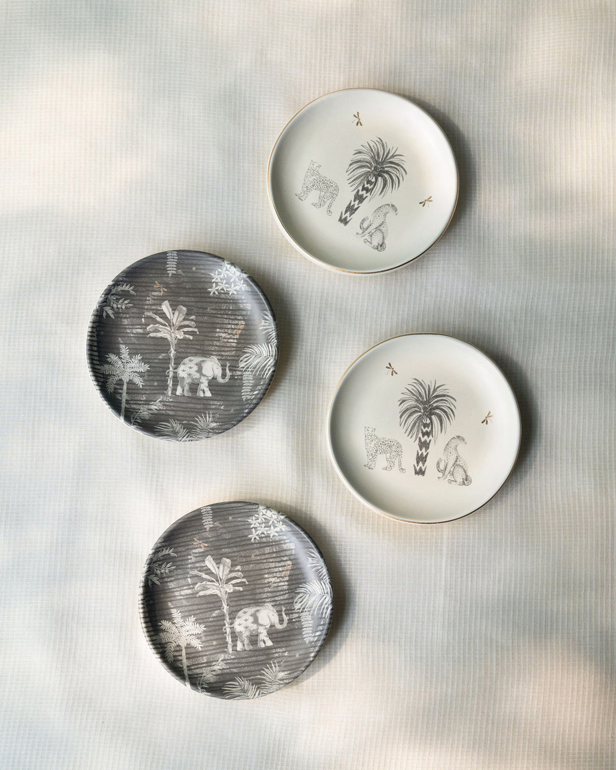 Periyar Tea Plates set of four, two grey and two white with palm and animal designs.