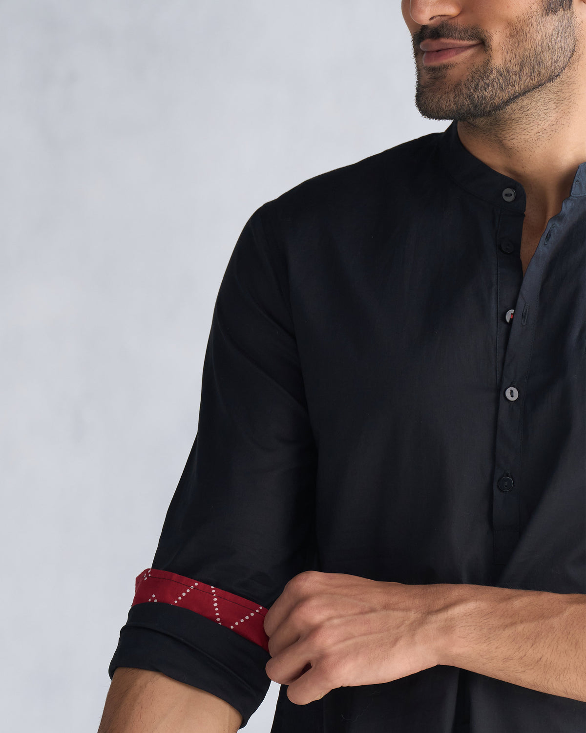 Close-up of a black Pondicherry kurta sleeve rolled to show red printed lining.