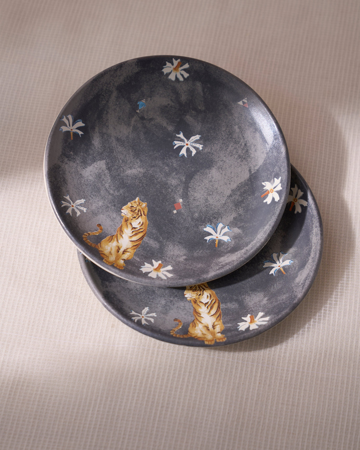 Stacked charcoal Nadi quarter plates showing matching tiger and flower prints.