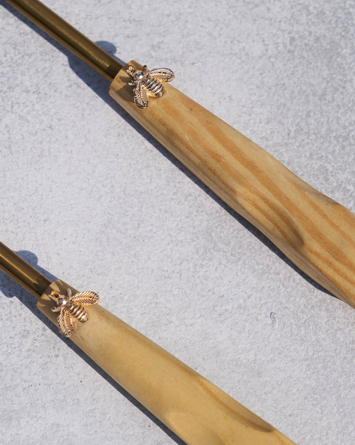 Close-up of Bee Salad Server handles showing gold bee motifs on wood.