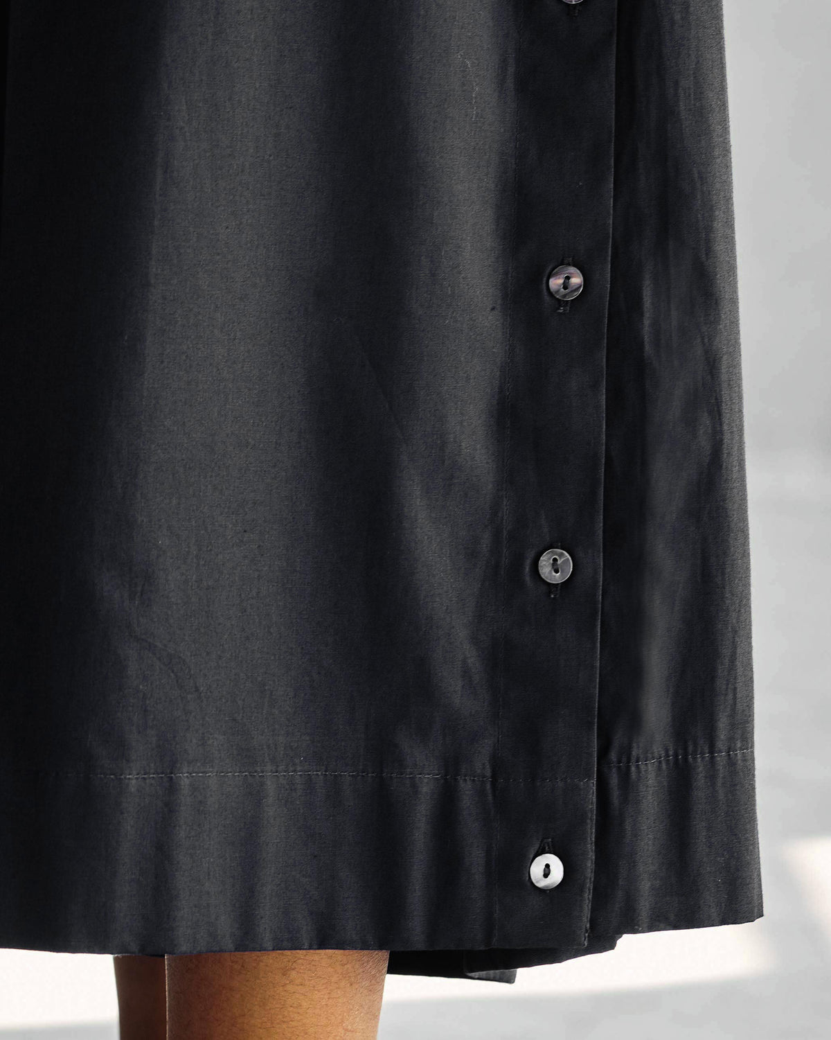 Close-up of black Pleated Flare Culottes showing the side button placket.