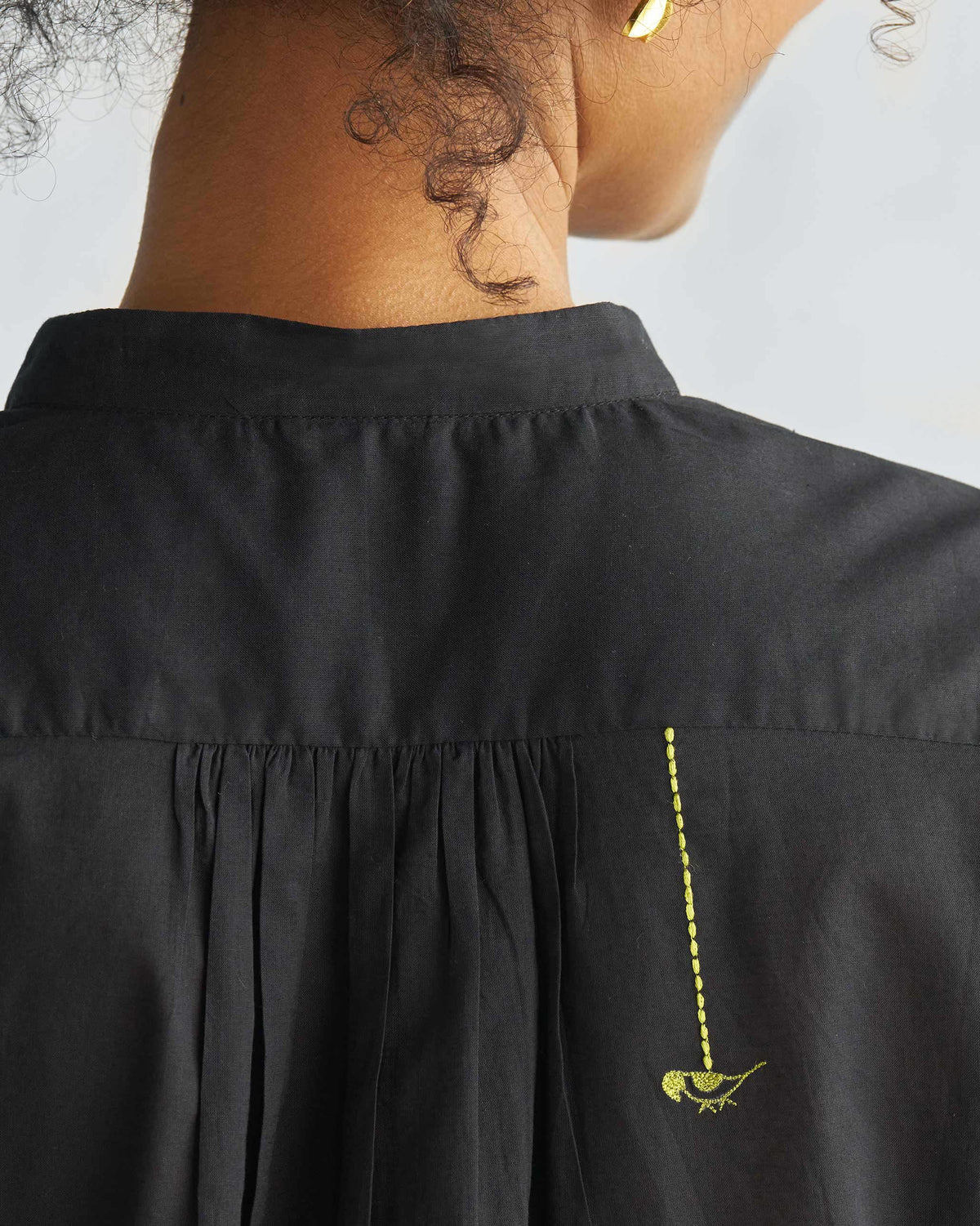 Close-up of the back of a black mandarin collar top with a bird on the yoke.