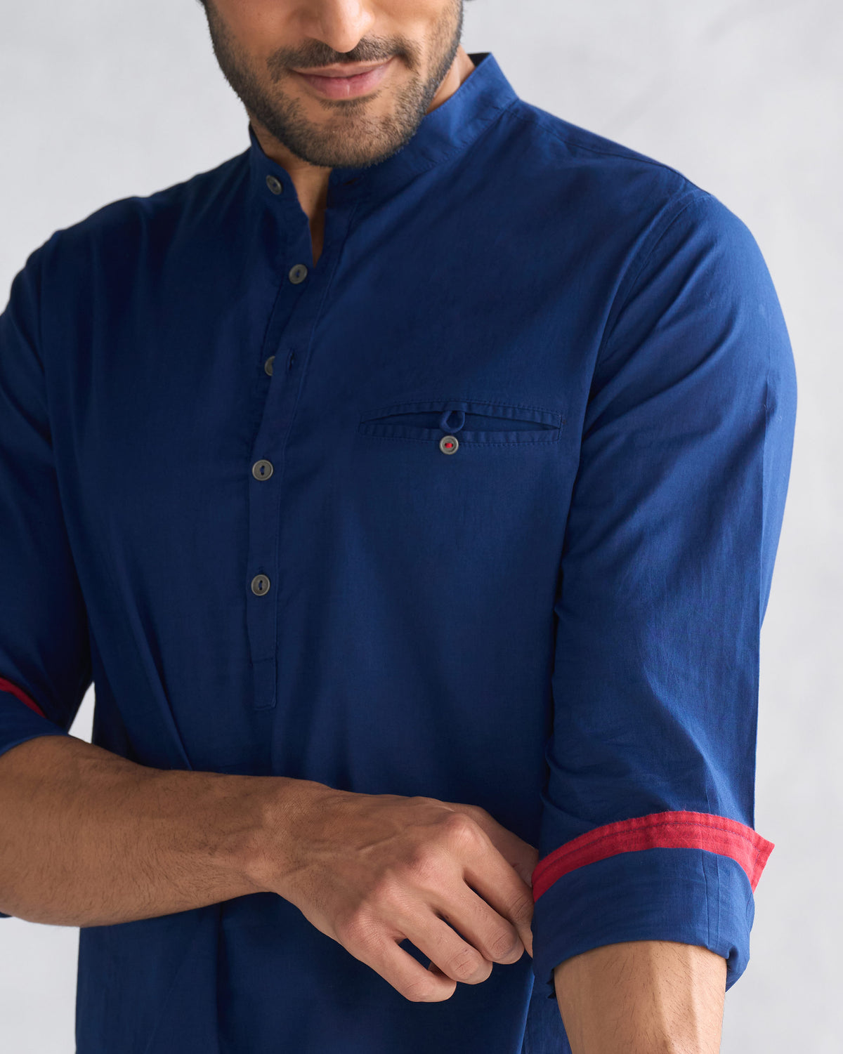 Close-up of a navy Pondicherry kurta showing collar, pocket, and red cuffs.