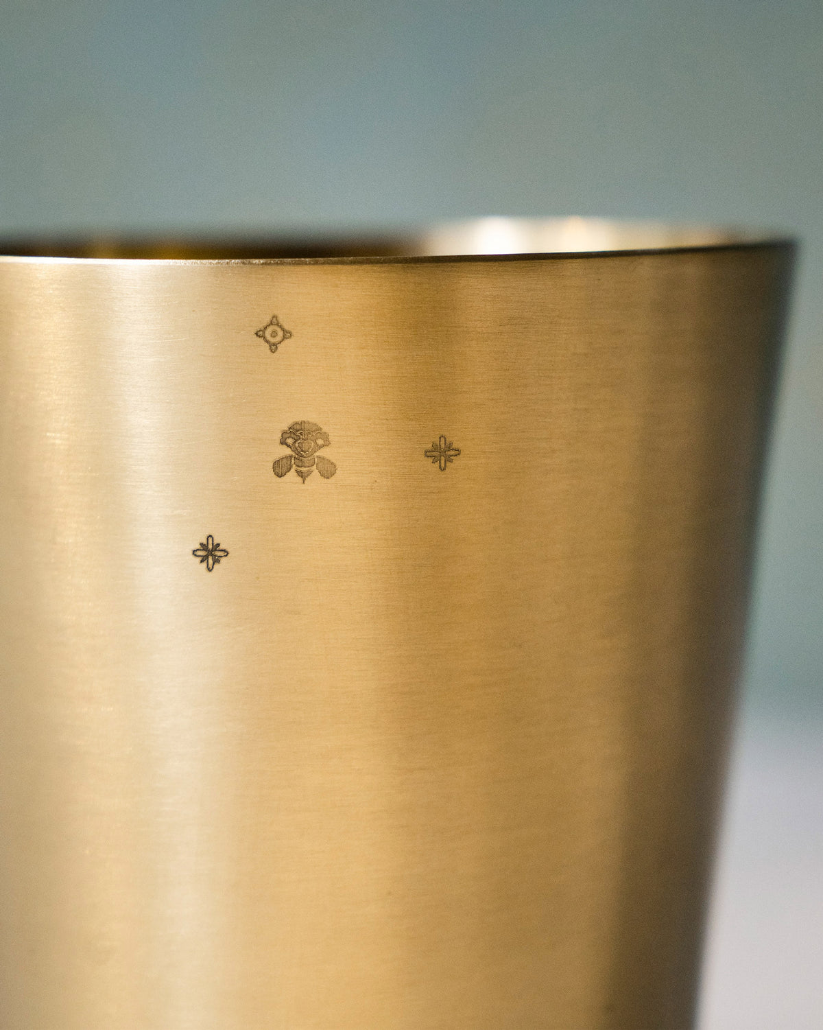 Close-up of Madhu glass showing a stamped bee and stars near the rim.