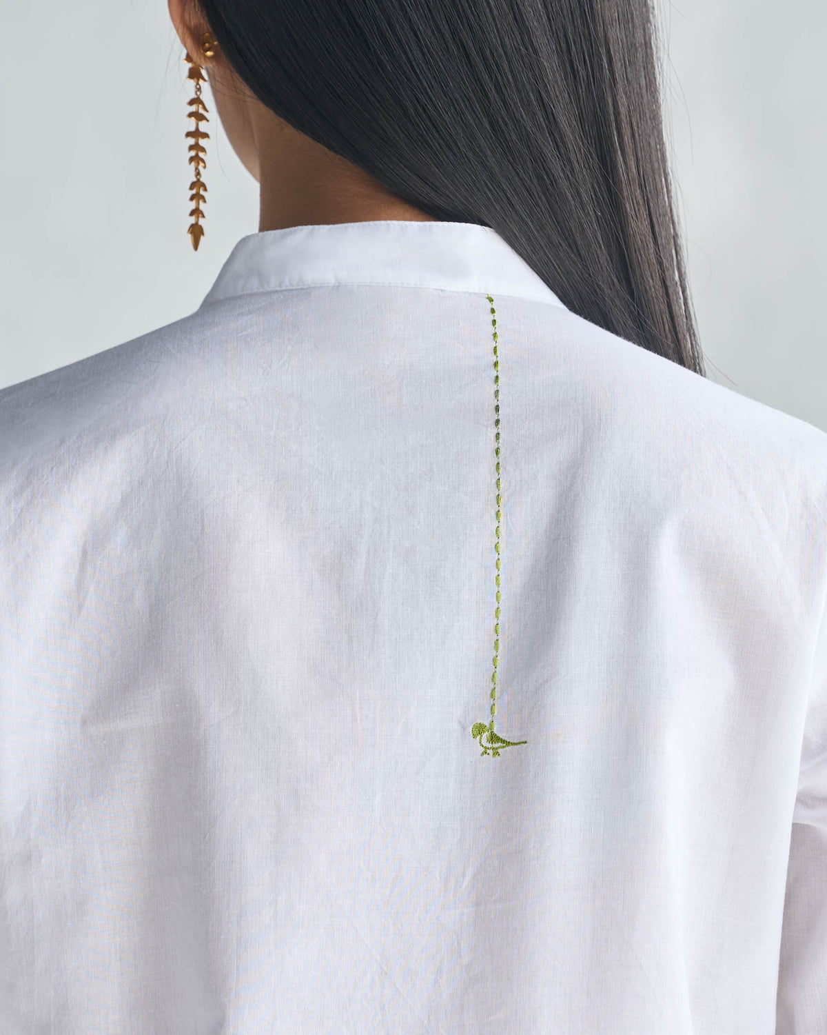 Close-up of the back of a white long kurta with a lime-green bird motif.