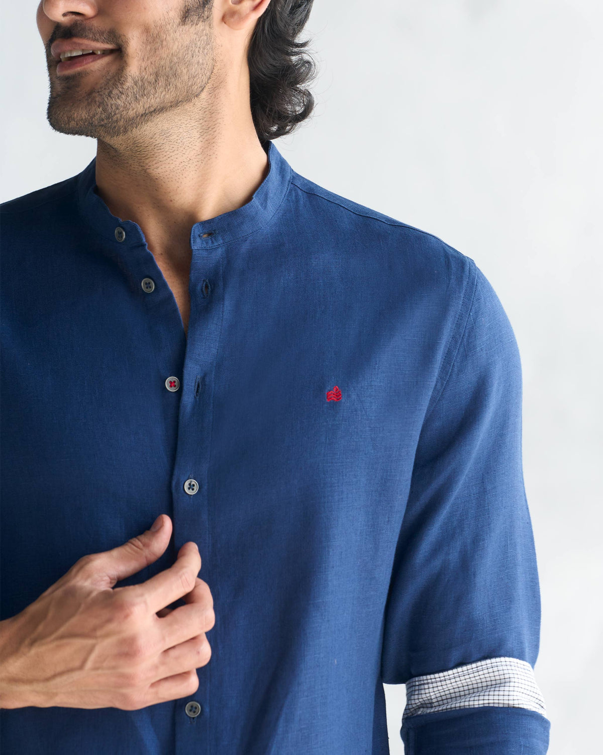 Close-up of a navy Nawab shirt showing a small red embroidered motif on the chest.