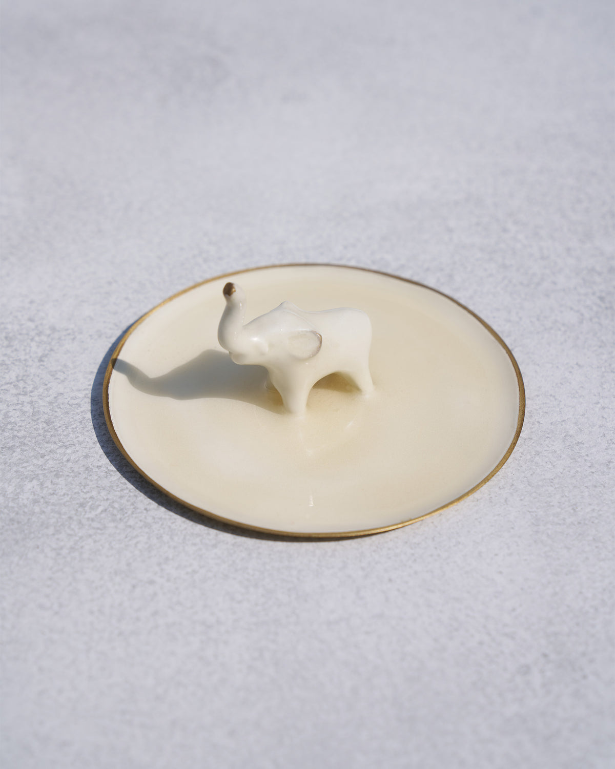 Angled view of an Ele trinket tray with a gold rim and white elephant figure.