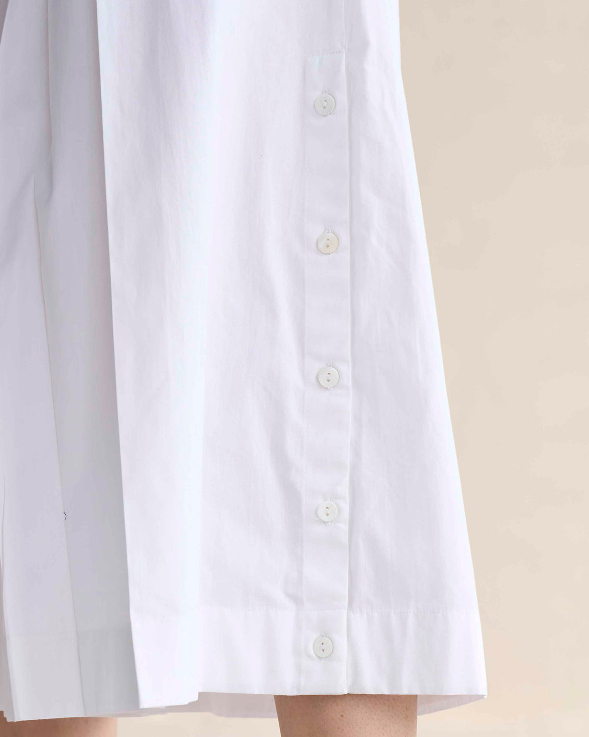 Close-up of white culottes showing a vertical row of side buttons.