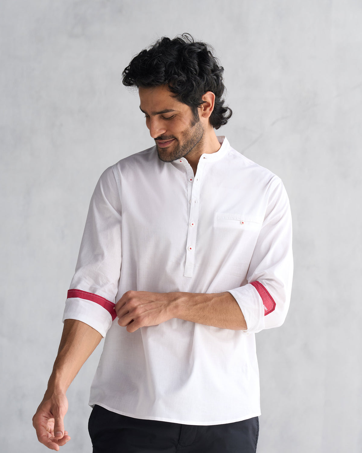 Three-quarter view of a white Pondicherry shirt with red cuff trim worn by a person.