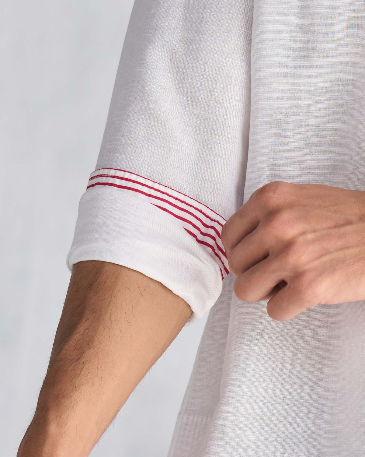 Close-up of the red-striped cuff lining on a white Chandni Chowk kurta.