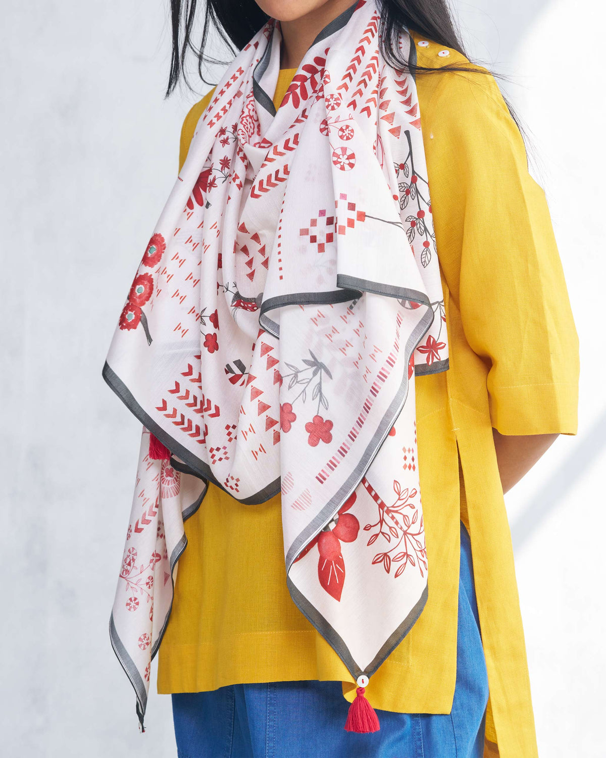 Close-up of Sugato scarf showing red floral motifs and a grey border.
