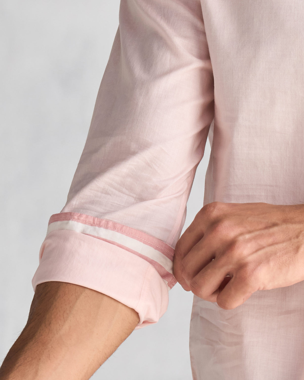 Close-up of a pink Pondicherry shirt showing a rolled sleeve with a white and pink trim.