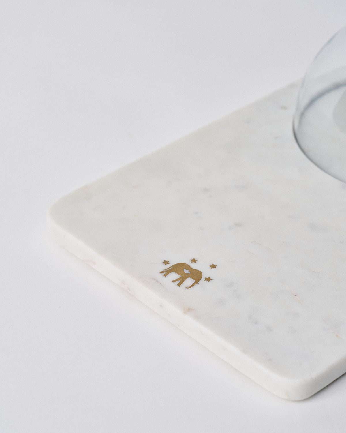 Close-up of the gold elephant motif on the white marble Ele cheese cloche.