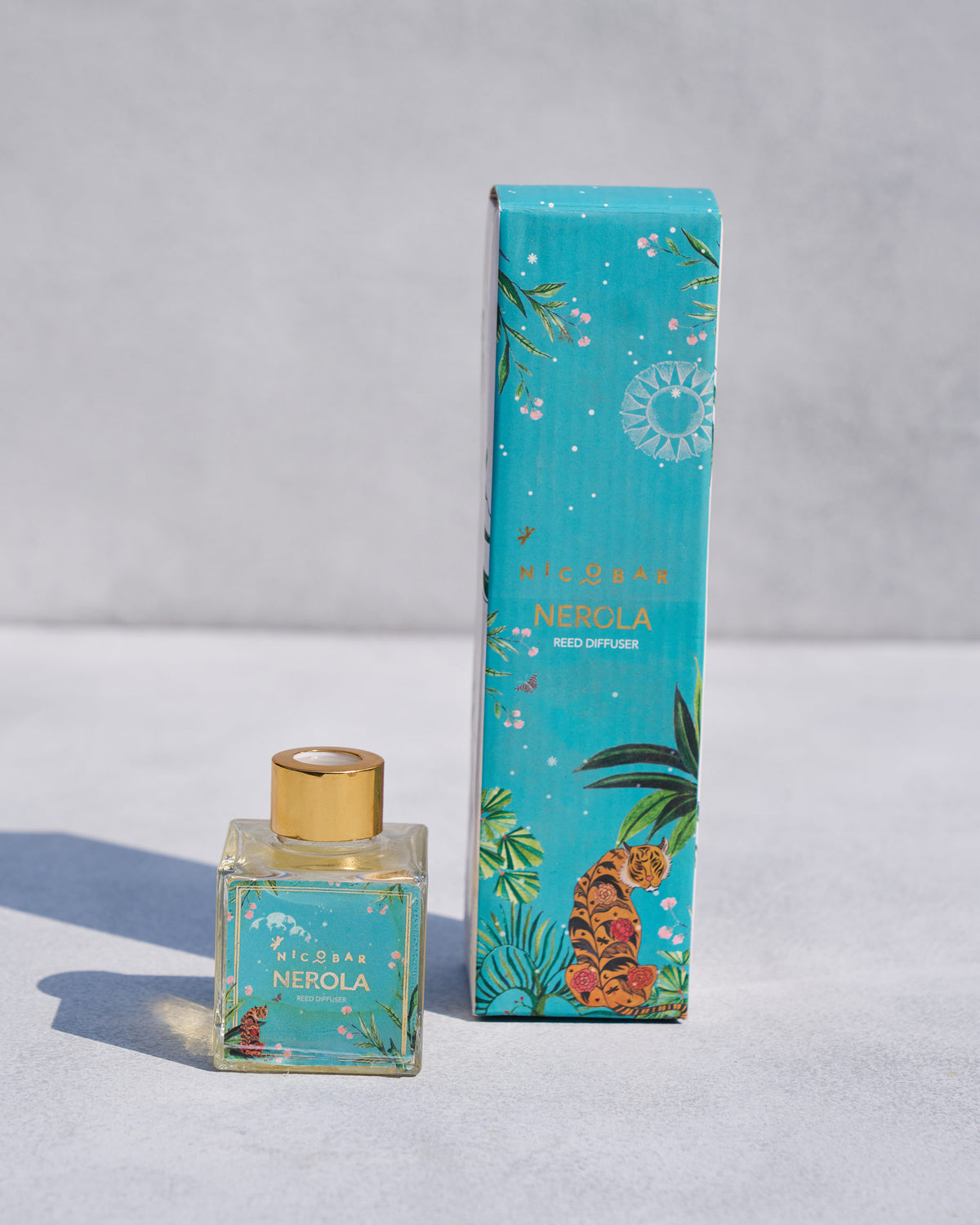 Nerola reed diffuser standing beside its teal gift box.