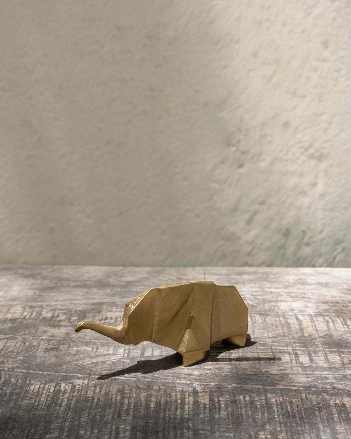 Gold Elephant origami sculpture on a wooden table.