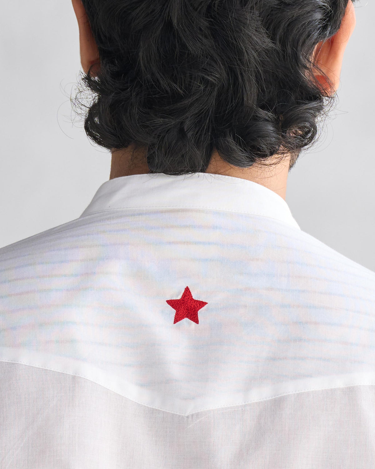 Close-up of a red star on the striped yoke of a white Pondicherry Kurta.