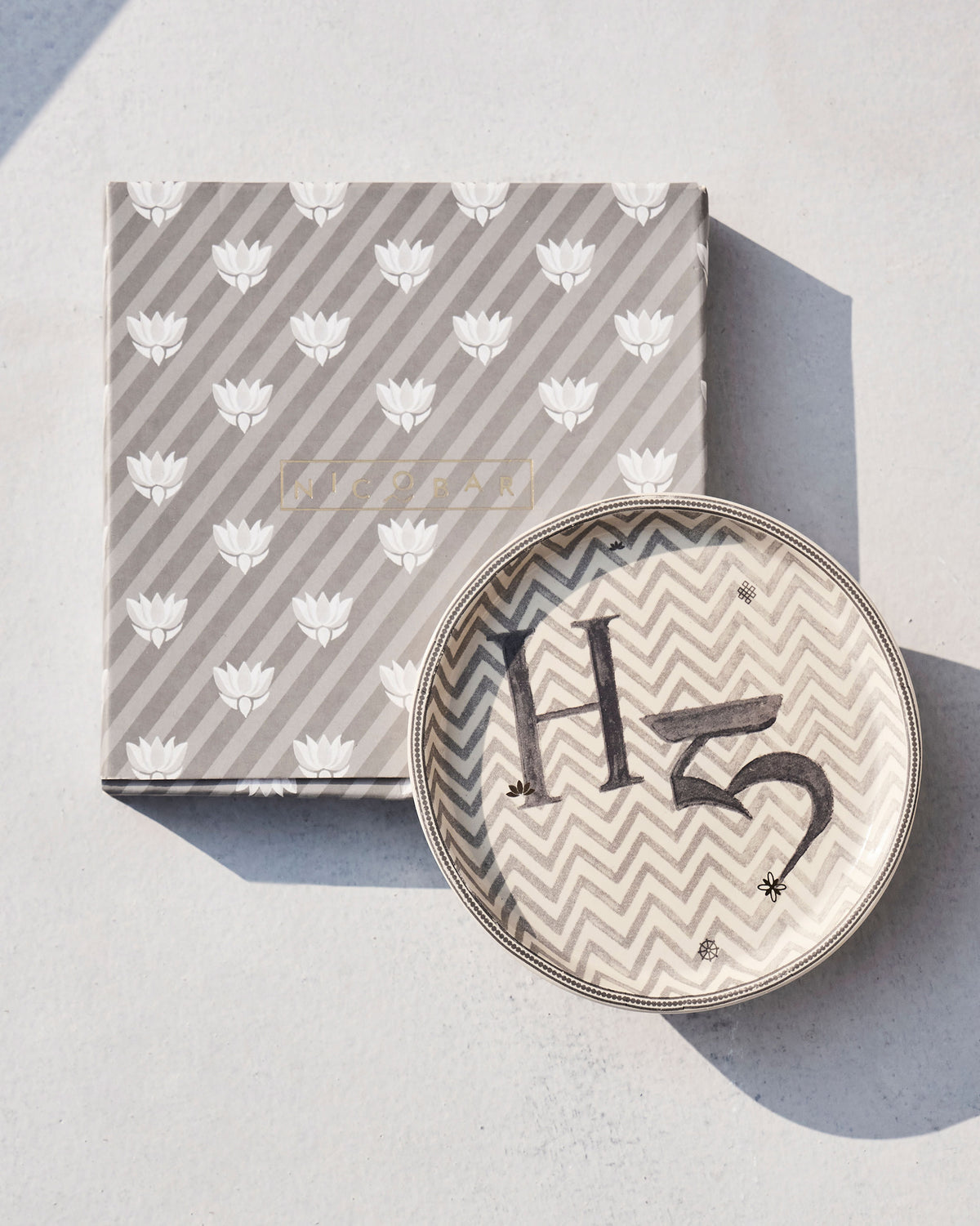 Akshar Coaster with a letter H set on its lotus-print gift box.