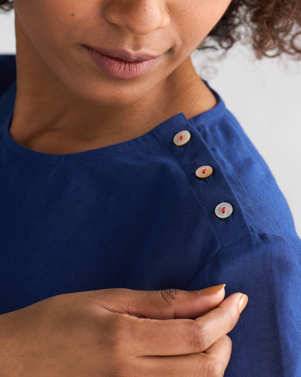 Close-up of a navy High slit top shoulder with three small buttons.