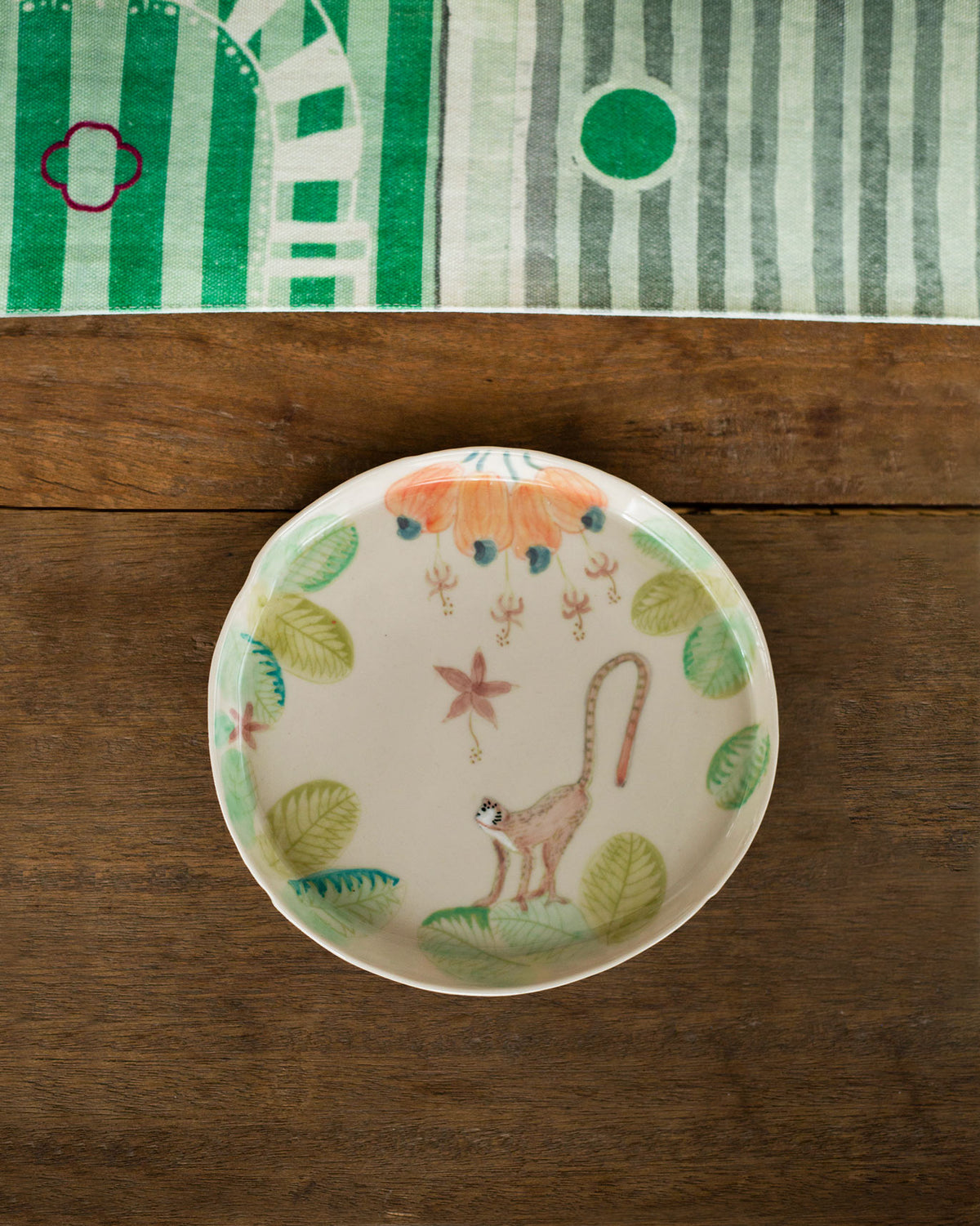 Mandovi dessert plate with a monkey, peach flowers and green leaves.
