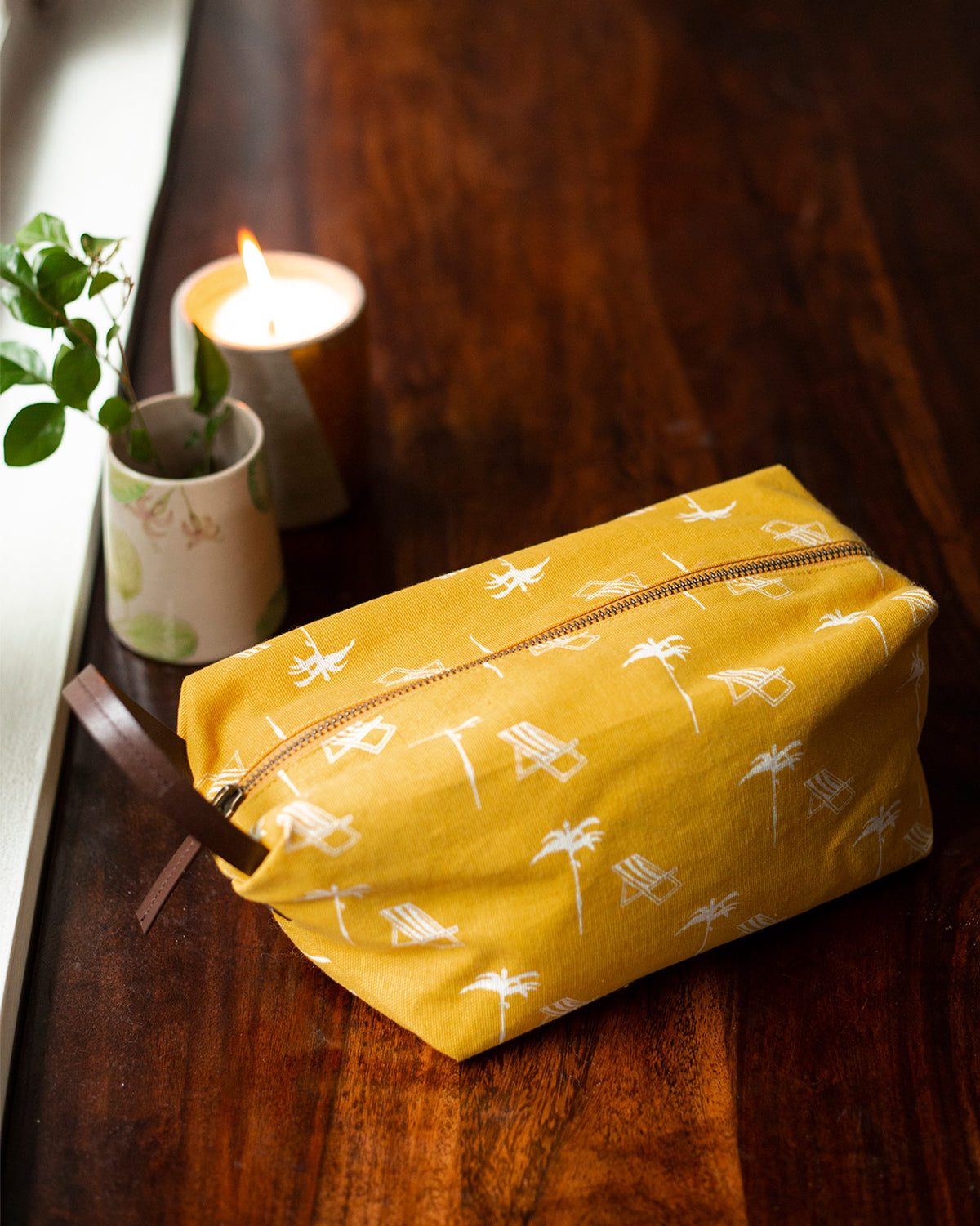 Coast Toilet Case in yellow with a white palm tree print and leather strap.
