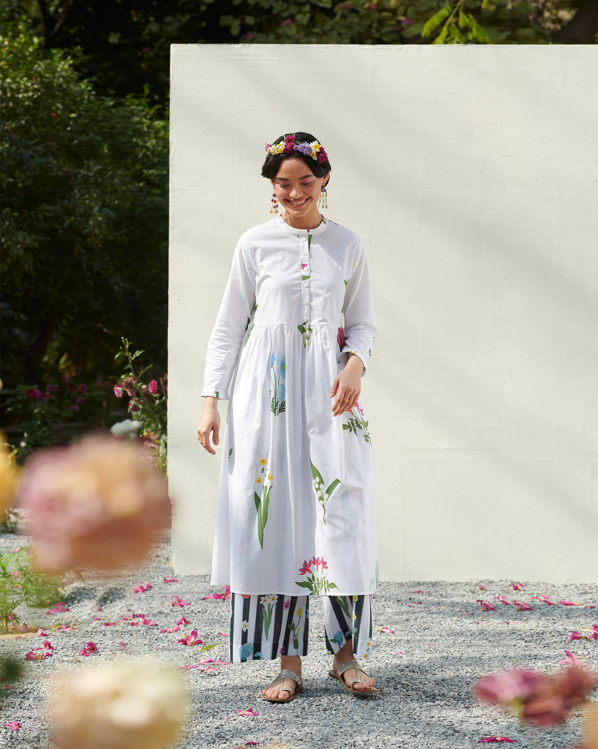 Person wearing a white pleat-front kurta with multicolour floral prints.
