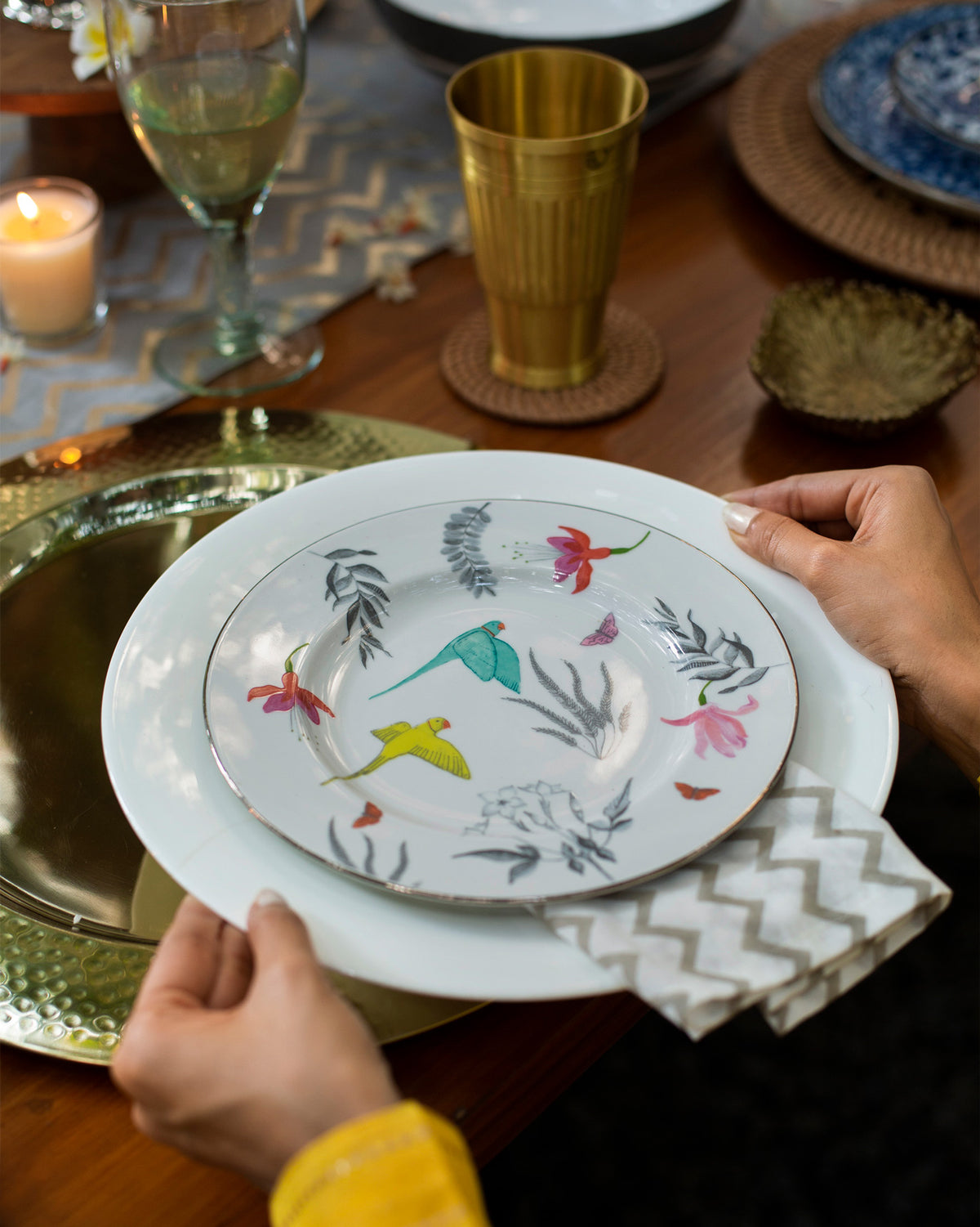 Person holding a Botanical quarter plate decorated with birds and leaves.