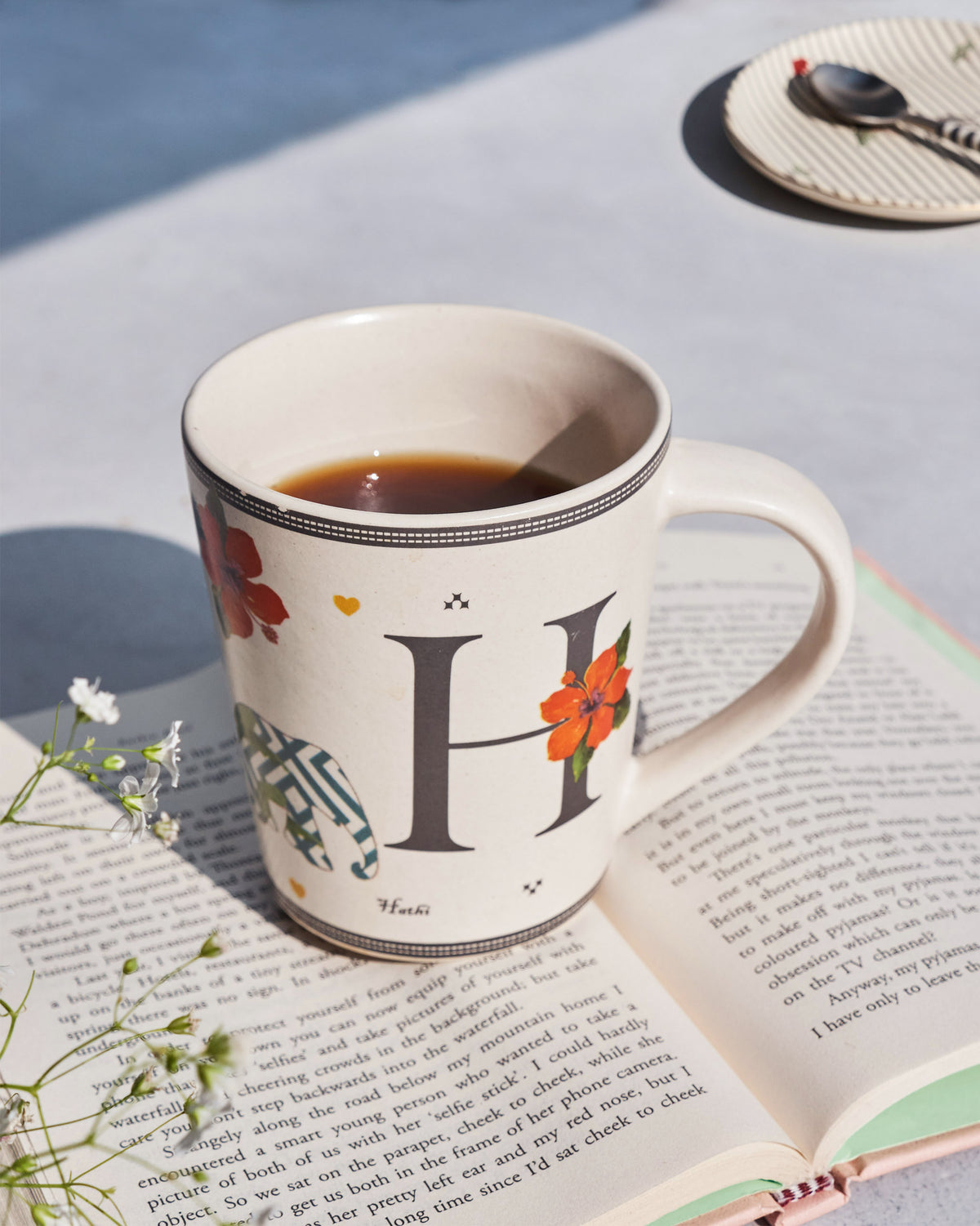 Hans mug with letter H, an elephant, and a flower filled with a dark drink.