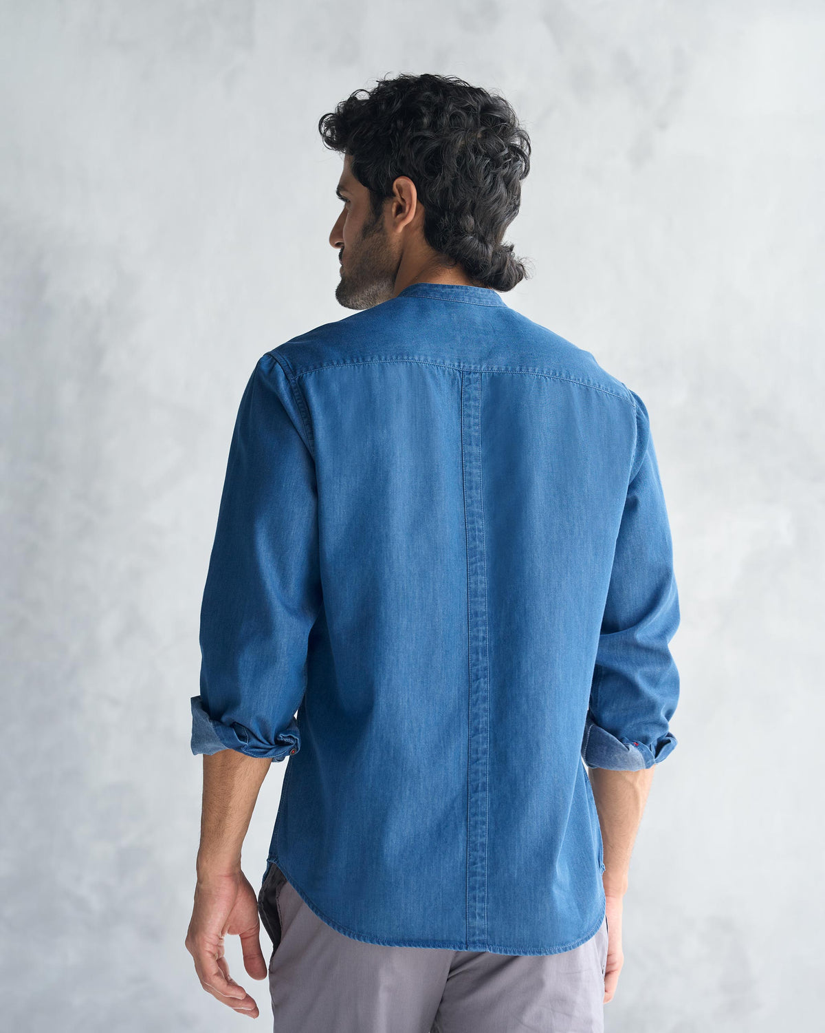 Back of a blue Nawab Shirt with a center seam and rolled sleeves.