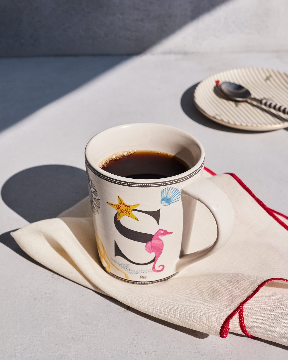 Coffee in a Singha mug with the letter S and ocean motifs.