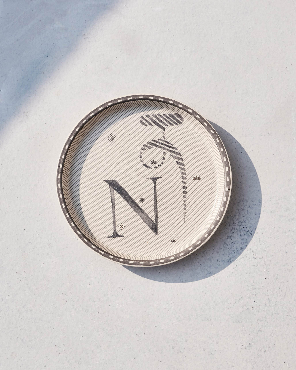 Akshar Coaster with a bold letter N on cream, seen from above.