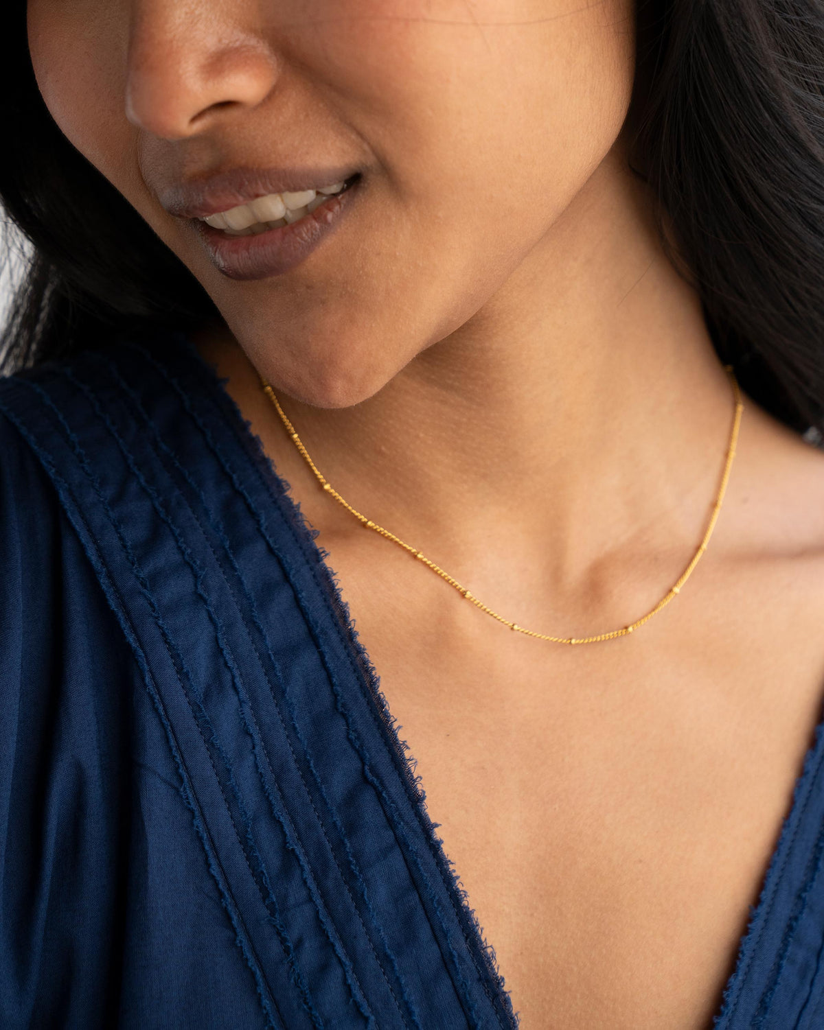 Close-up of an extra small gold Boondi Chain on a person's neck.