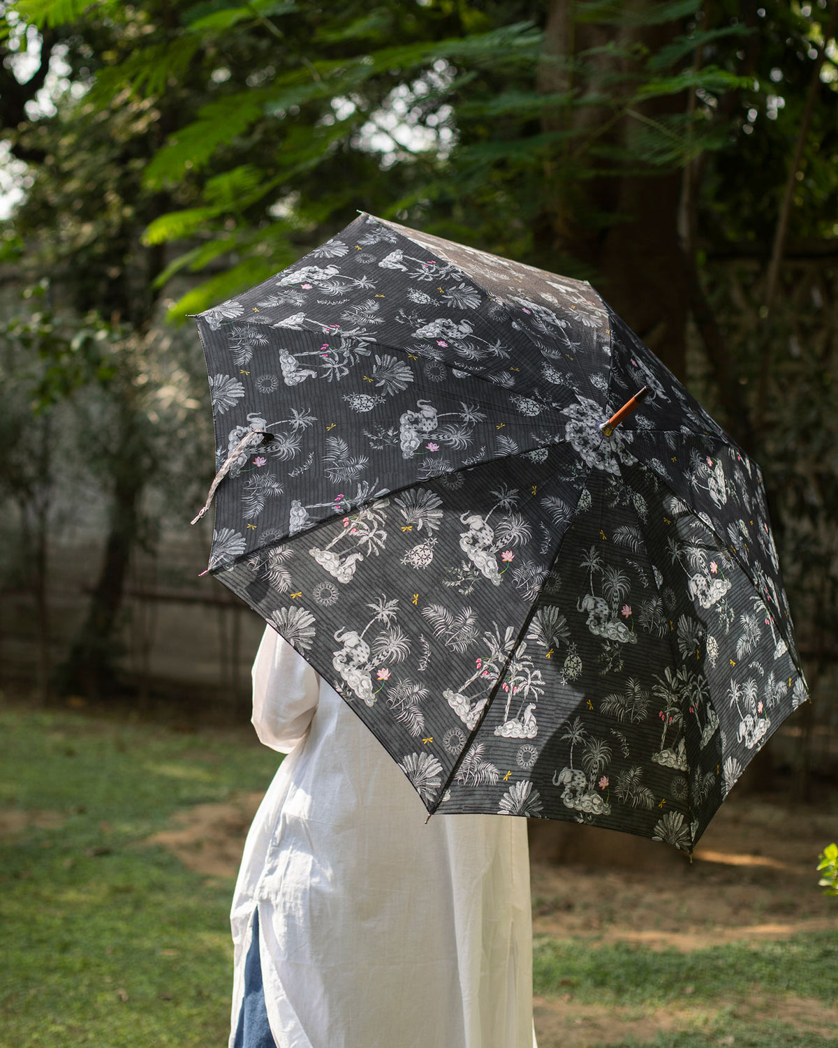 Person holding a black Periyar Umbrella with a white palm print.