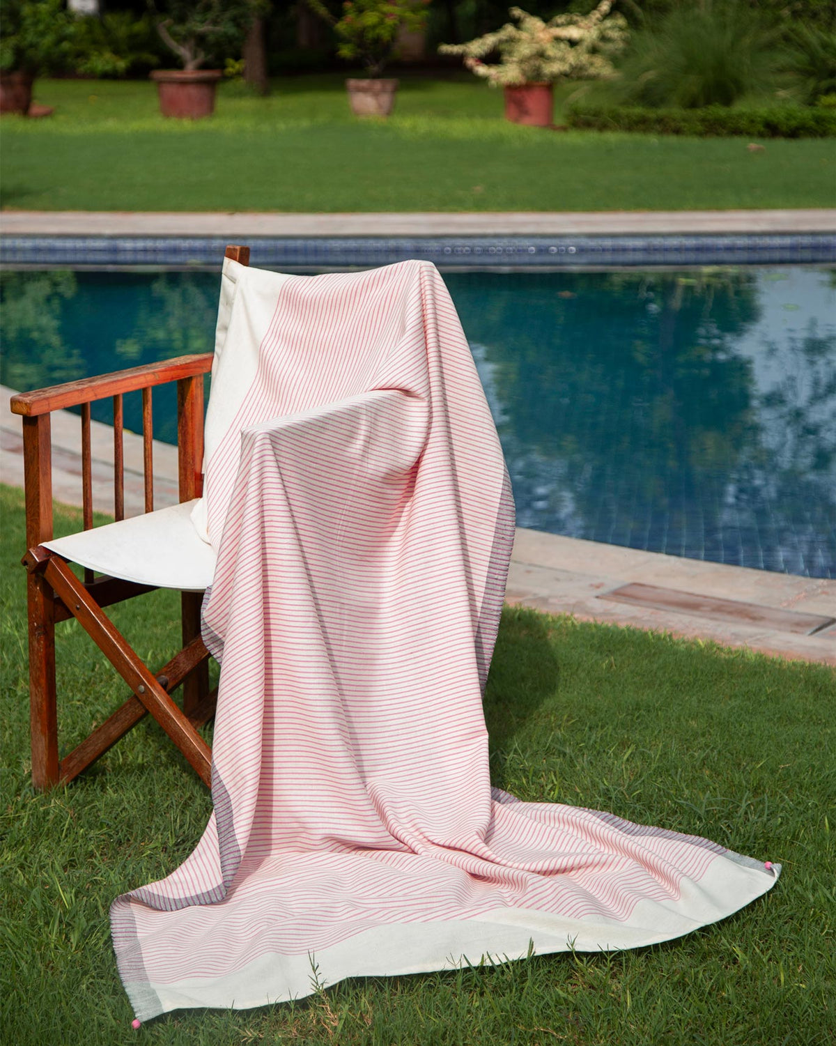 Coast Towel in pink stripes draped over a wooden chair.