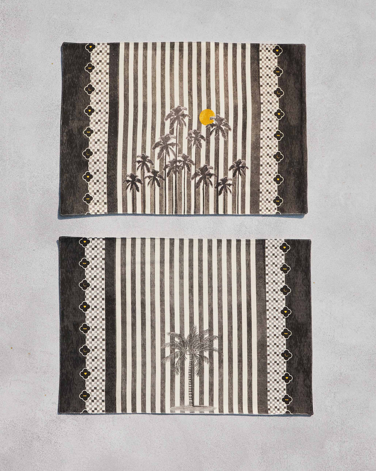 Pair of Midnight placemats with palm trees and stripes laid flat.