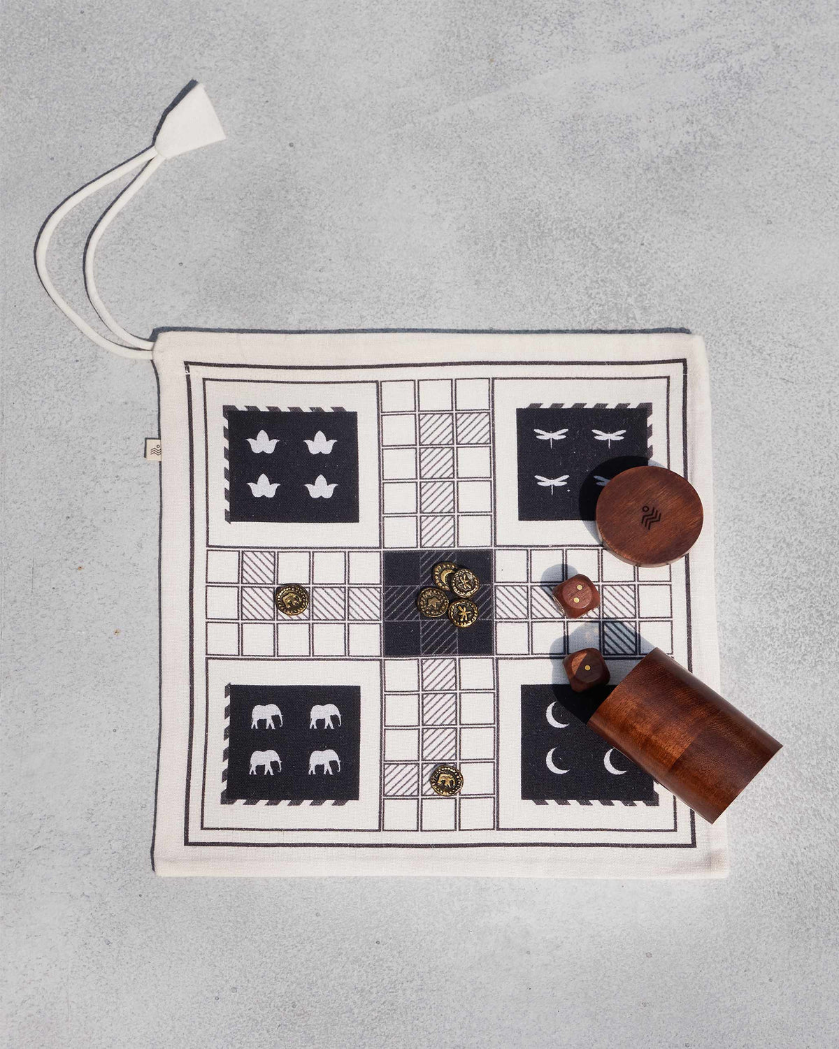 Nico Ludo cloth board laid flat with brass tokens, wooden dice, and a dice cup.