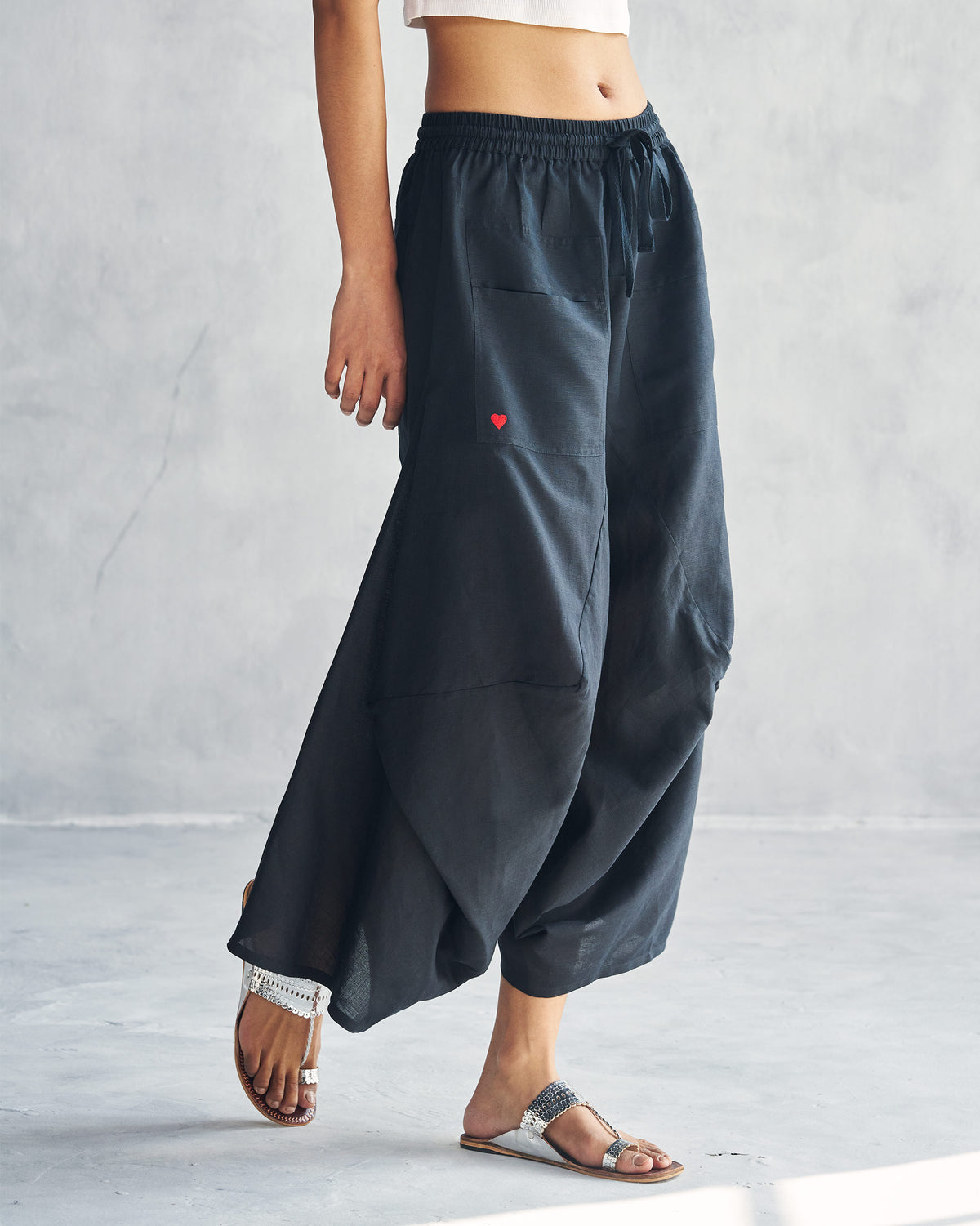 Side view of black Yoka trousers with a wide, flared leg.