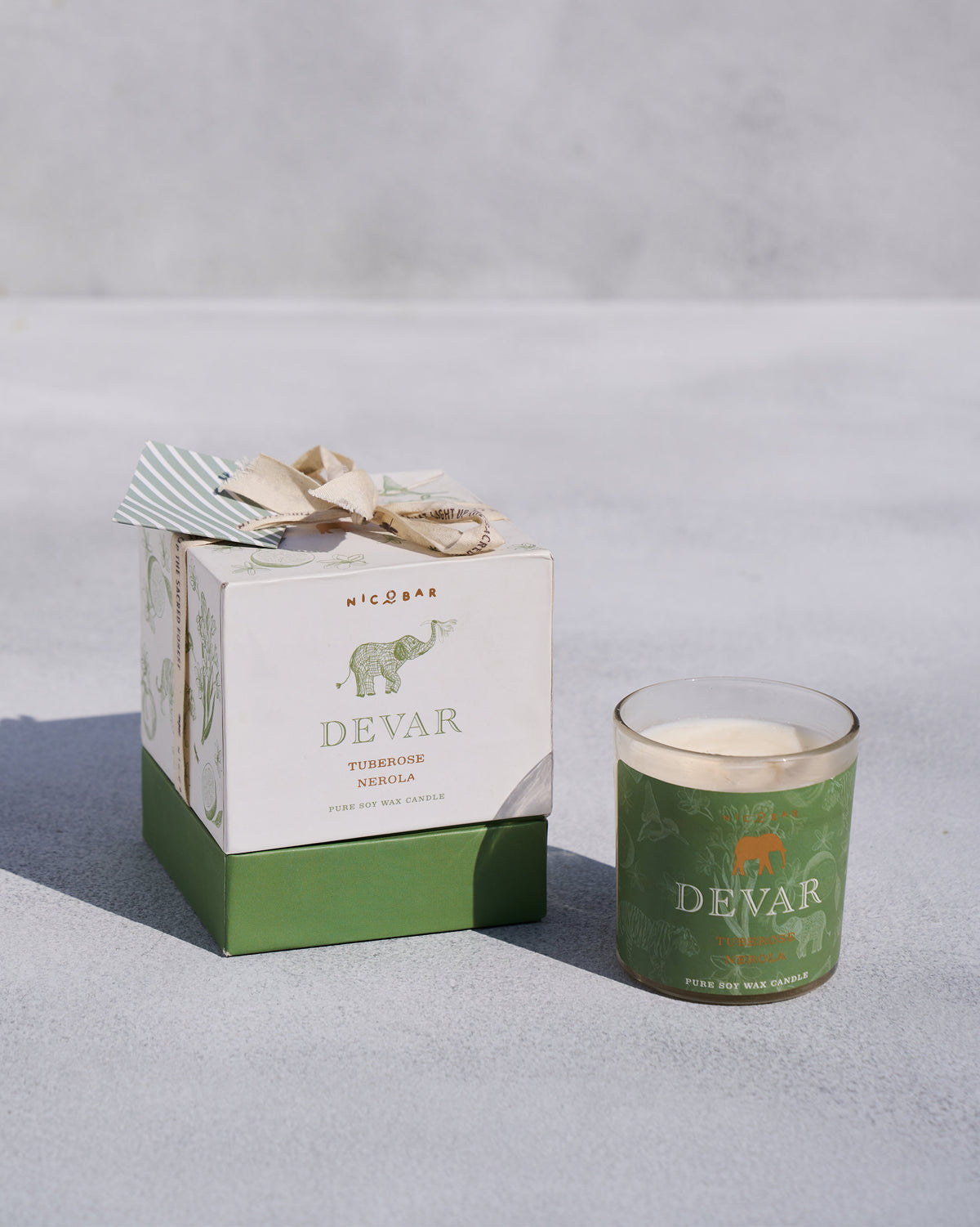 Devar candle in a green glass jar beside its gift box.