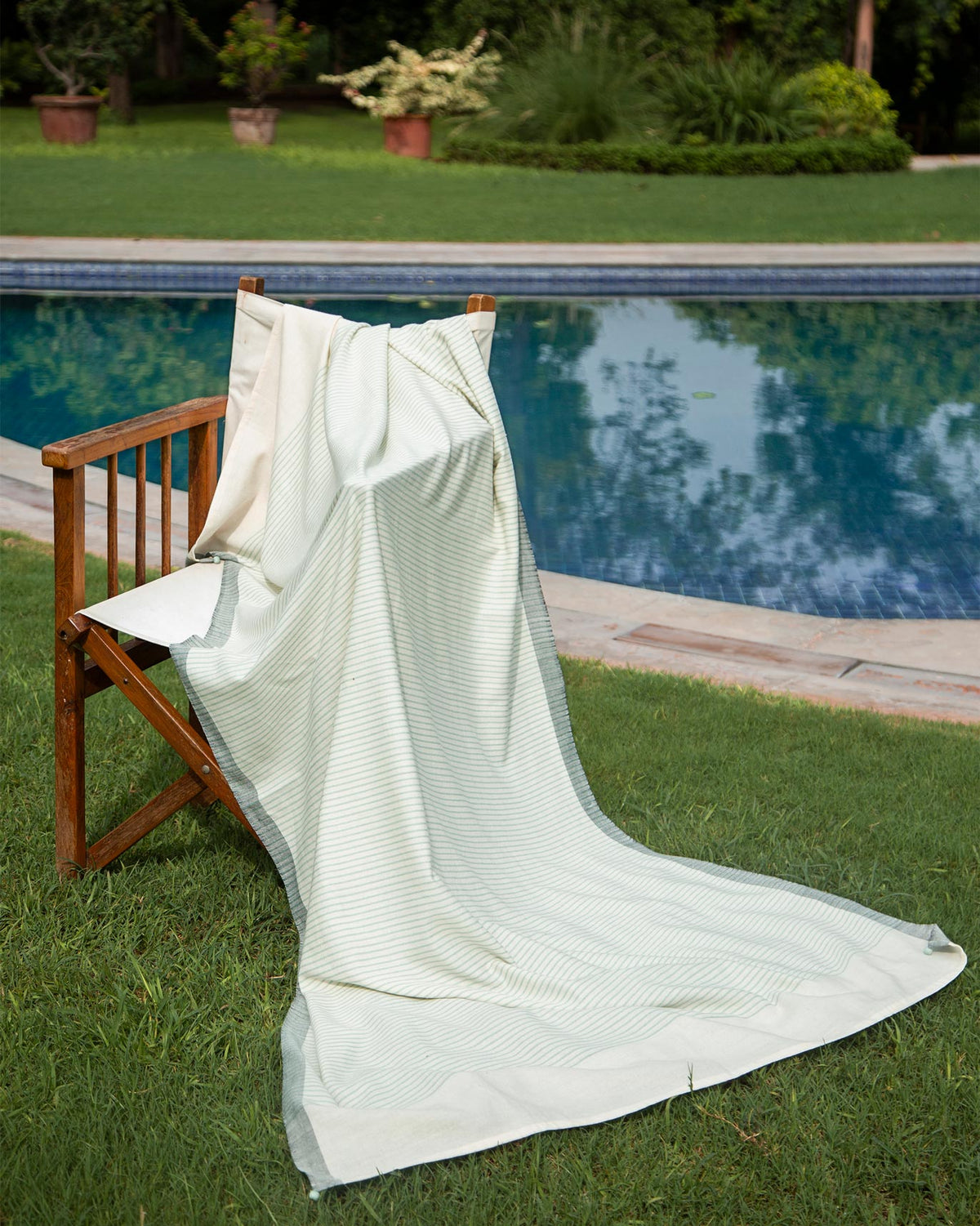 Coast Towel in aqua stripes draped over a wooden chair.