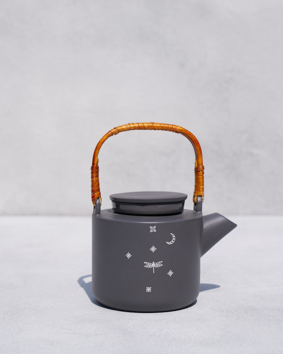 Taramandal charcoal teapot with rattan handle and white dragonfly motifs.