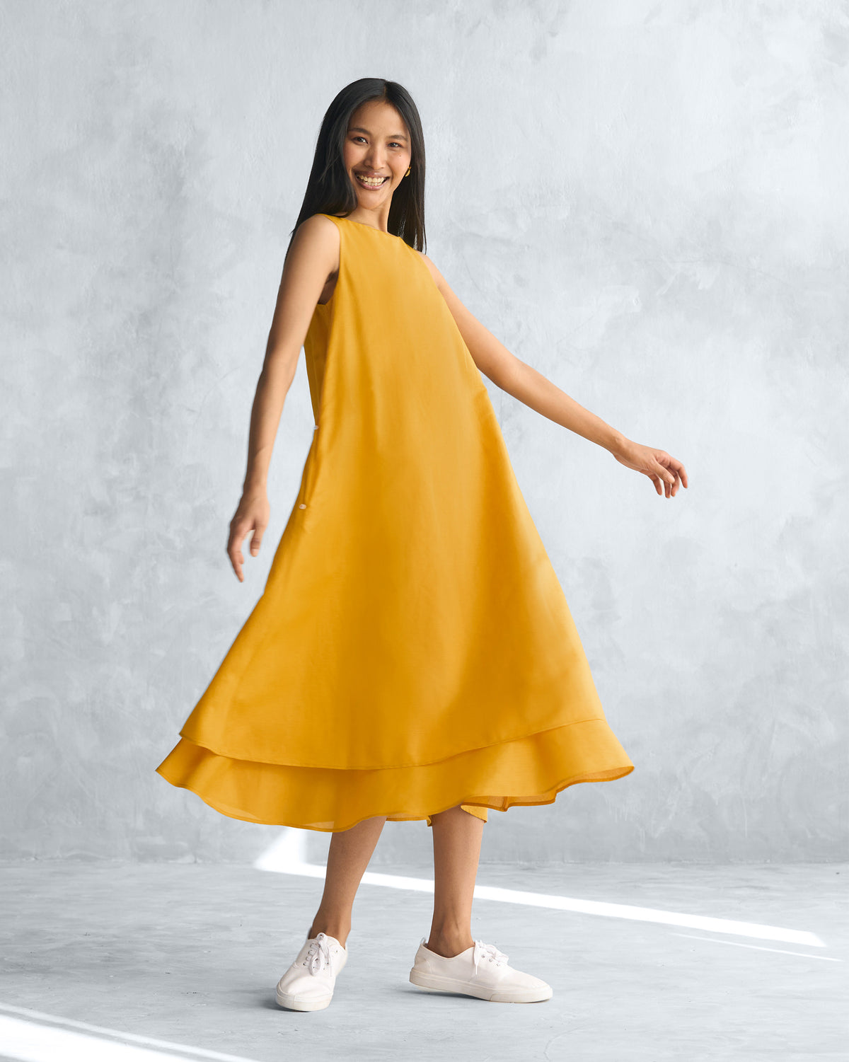 Person wearing a mustard yellow Double layer dress with a flared hem.