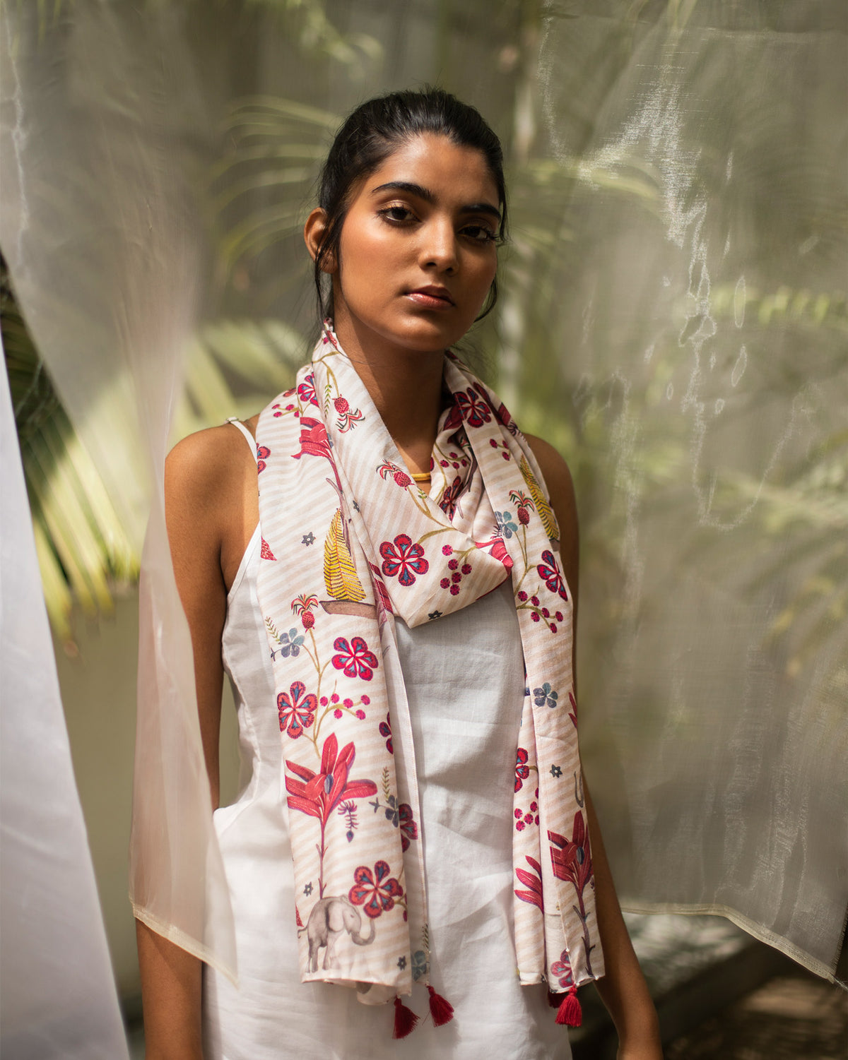 Person wearing a pink and cream Cascade Scarf with a red floral print.