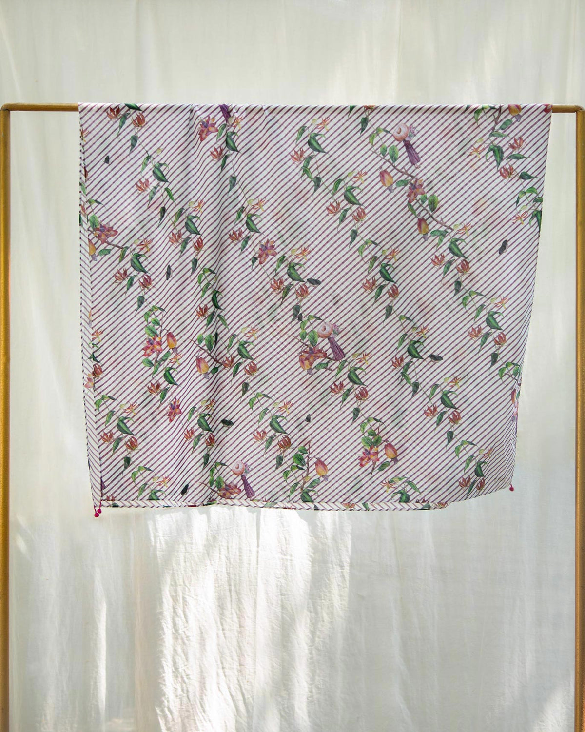 Riverine Sarong hanging on a gold rail, showing its floral print.
