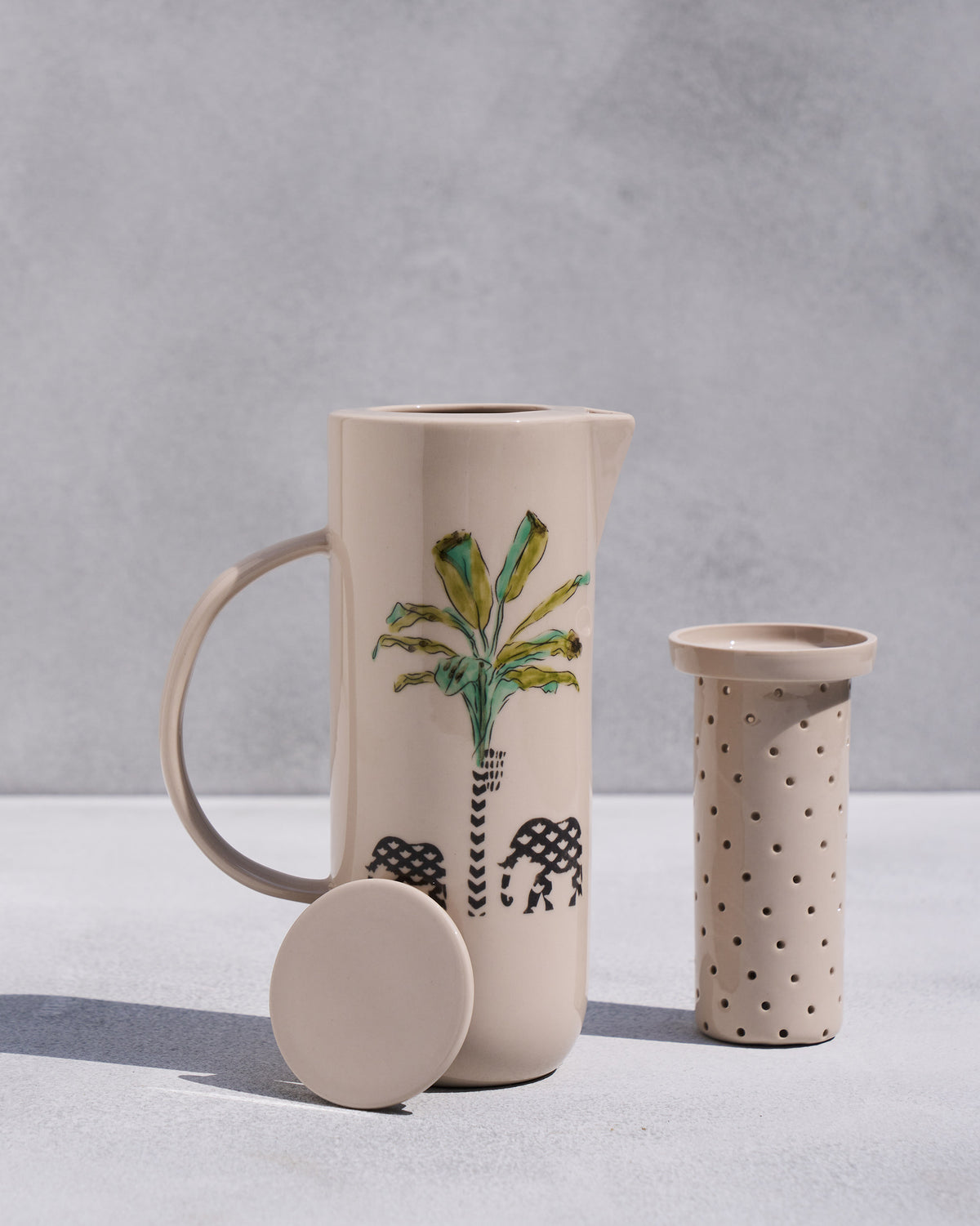 Ele carafe with palm and elephants, shown with infuser and lid.