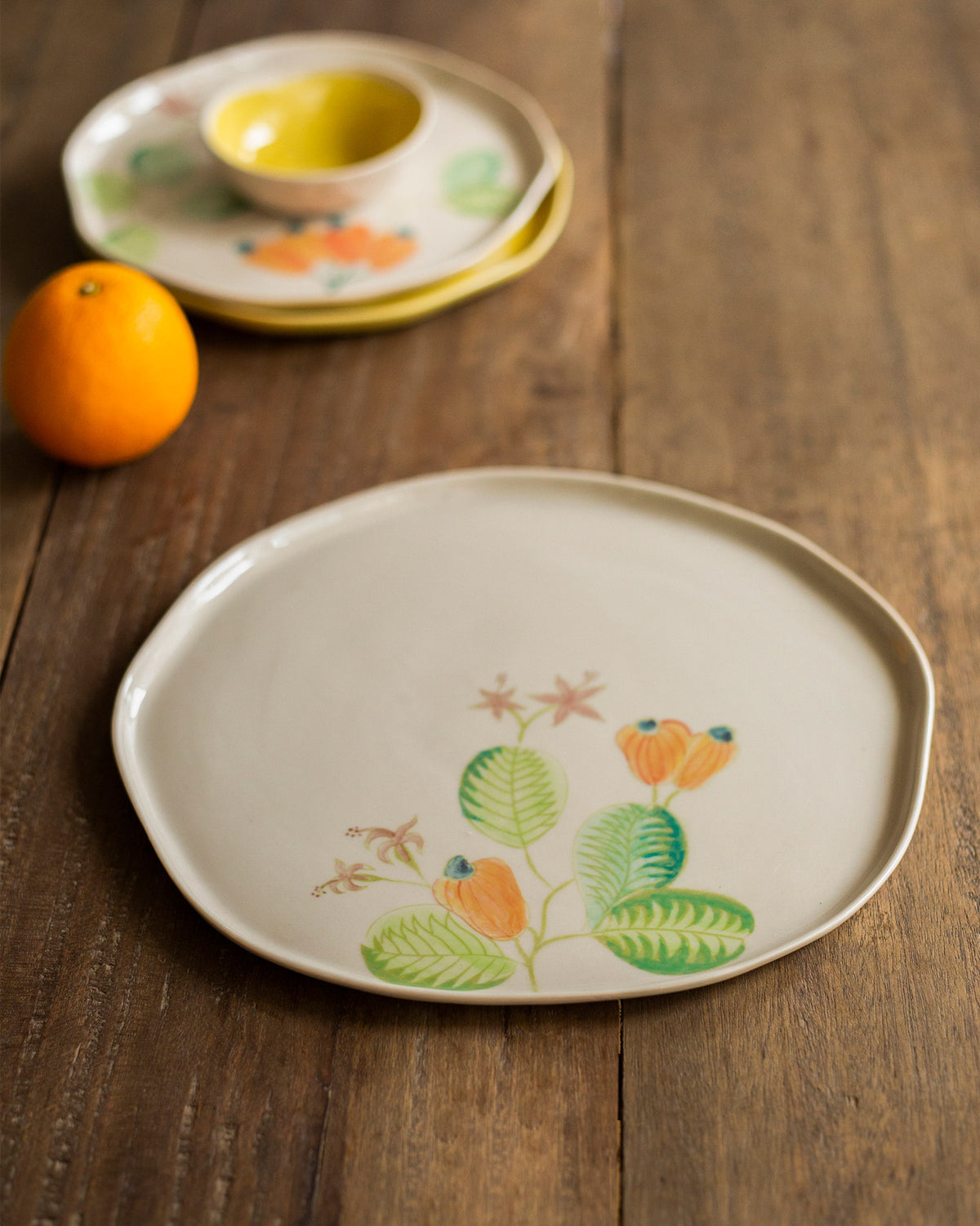 Mandovi Dinner Plate with an orange and green leaf motif on cream.