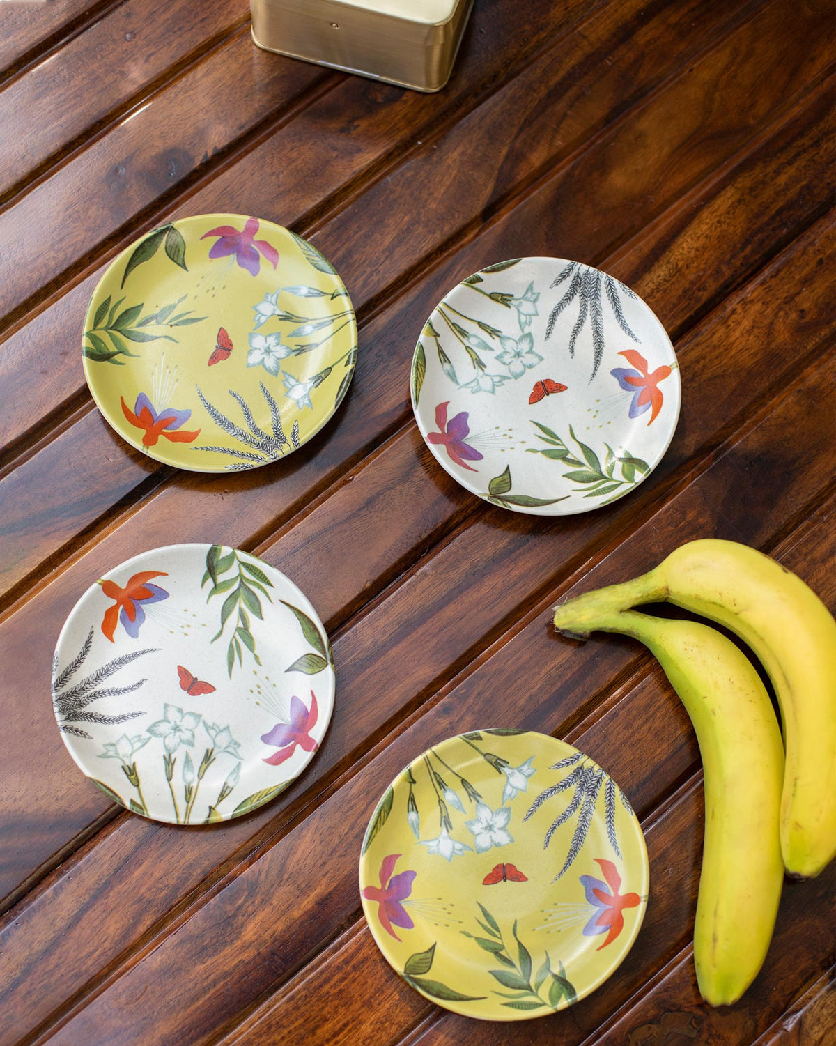 Set of four Botanical Tea Plates laid flat, in yellow and cream.