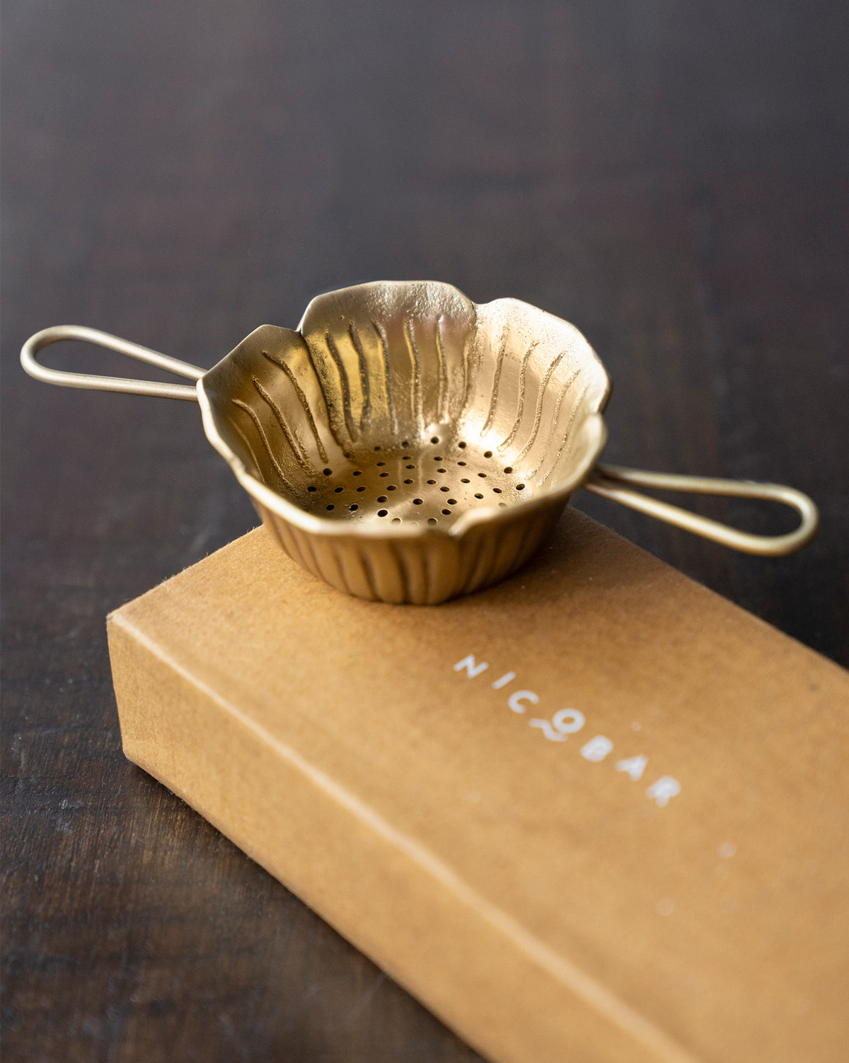 Brass Phool tea strainer on a Nicobar gift box.