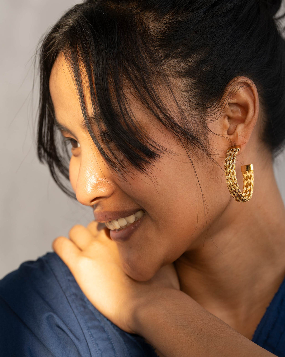 Side profile of Sea Shore Hoops with a braided gold texture on a person.