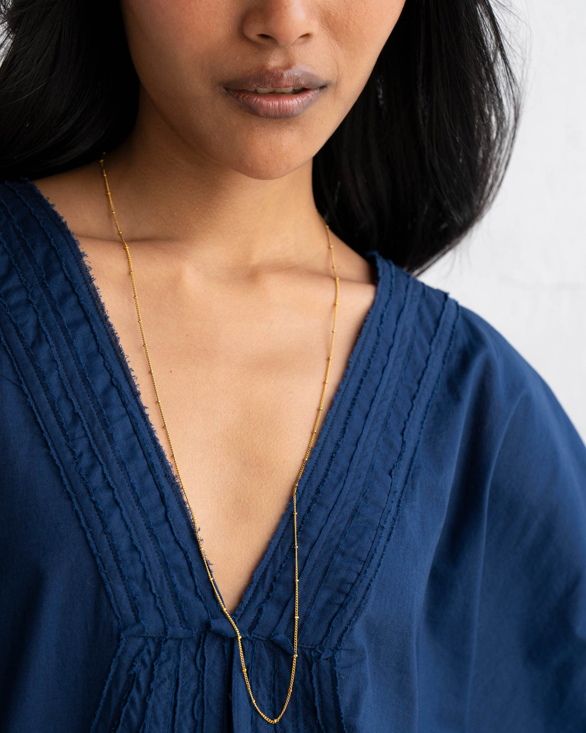 Person wearing Boondi Chain, a long gold chain falling into the neckline.