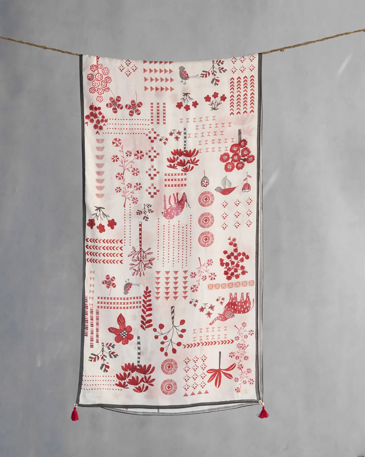 Sugato scarf hung flat, showing red birds, florals and geometric motifs on white.